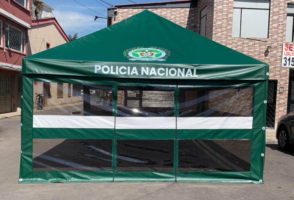 Vemos una carpa tradicional tipo kiosco de color verde y con logos de la Policía Nacional de Colombia