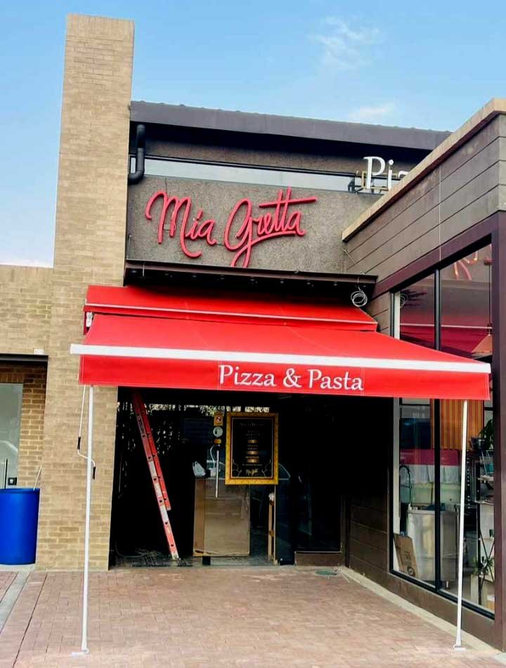Vemos un toldo plegable de color rojo y con el logo de un establecimiento de pizzas